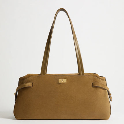 A tan suede handbag with dual shoulder straps and a small gold-tone metal logo plaque on the front, photographed against a clean white background.