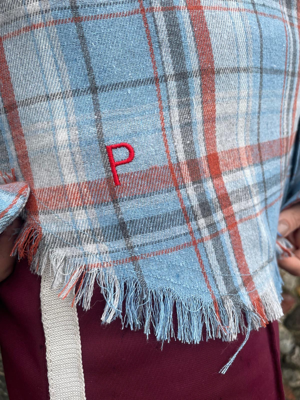 PARK Classic Shirt in Blue Plaid Plaid fabric with a red 'P' embroidered on it, held by hands.