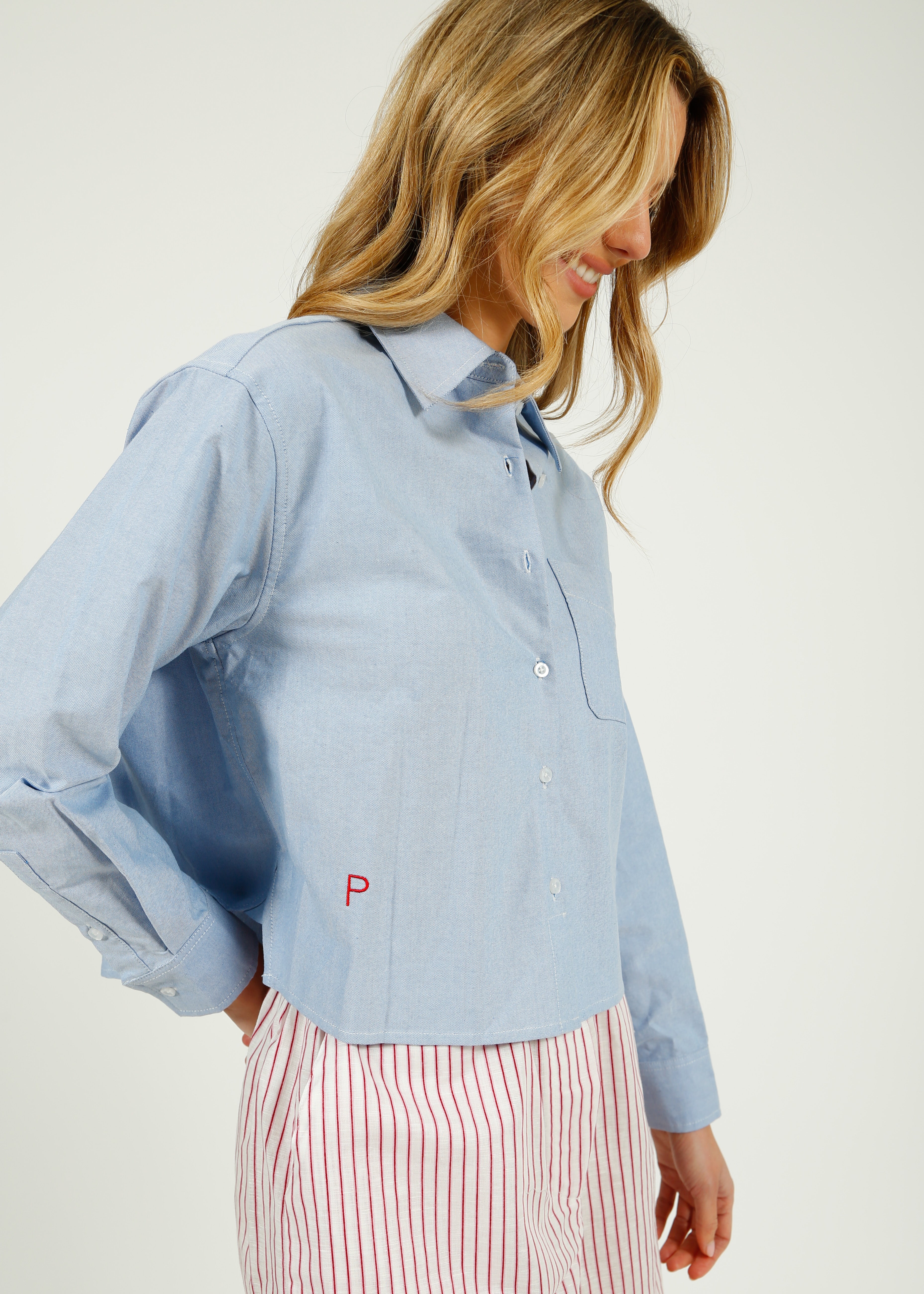 Woman wearing a light blue shirt with a logo on a white background