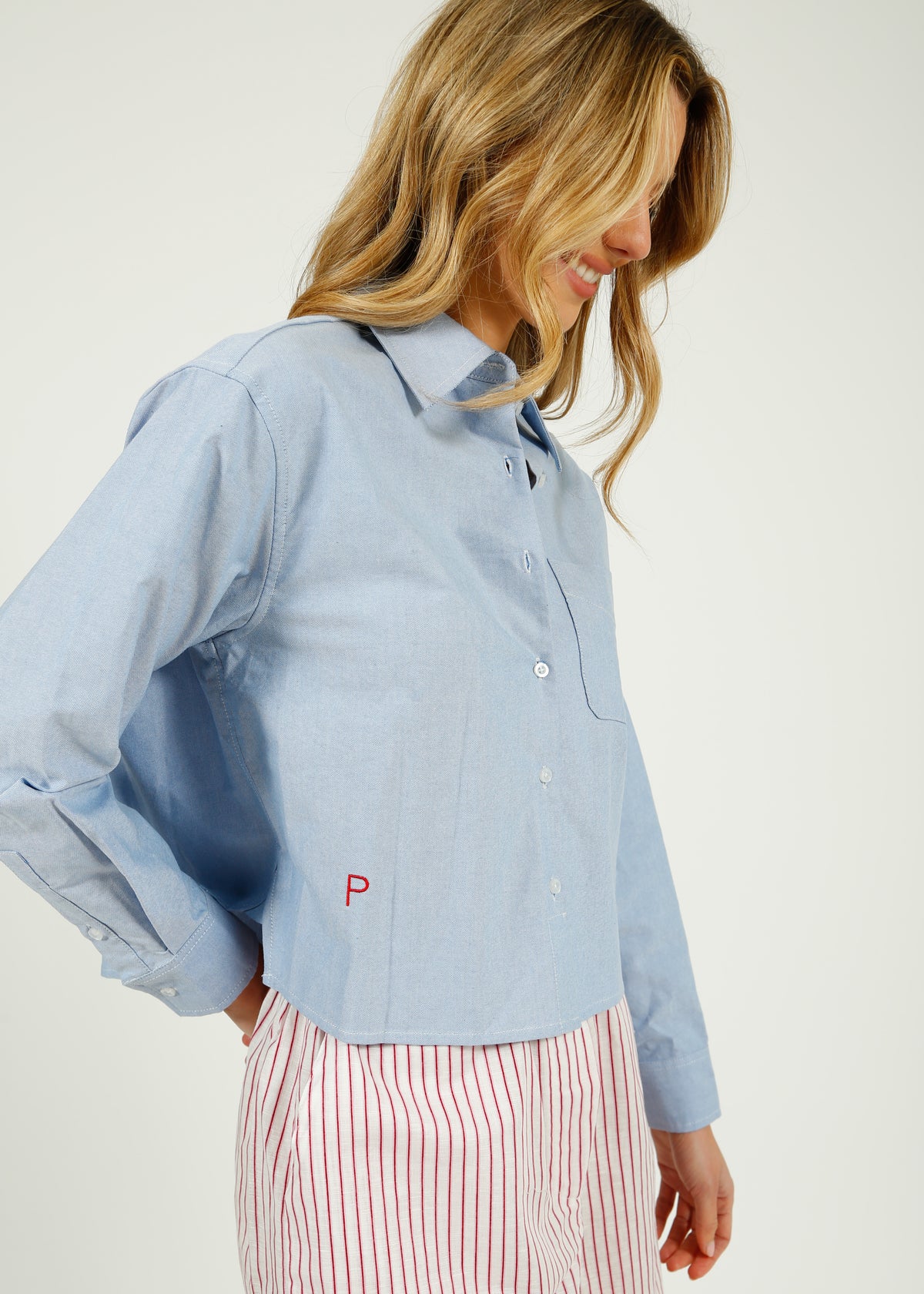 Woman wearing a light blue shirt with a logo on a white background