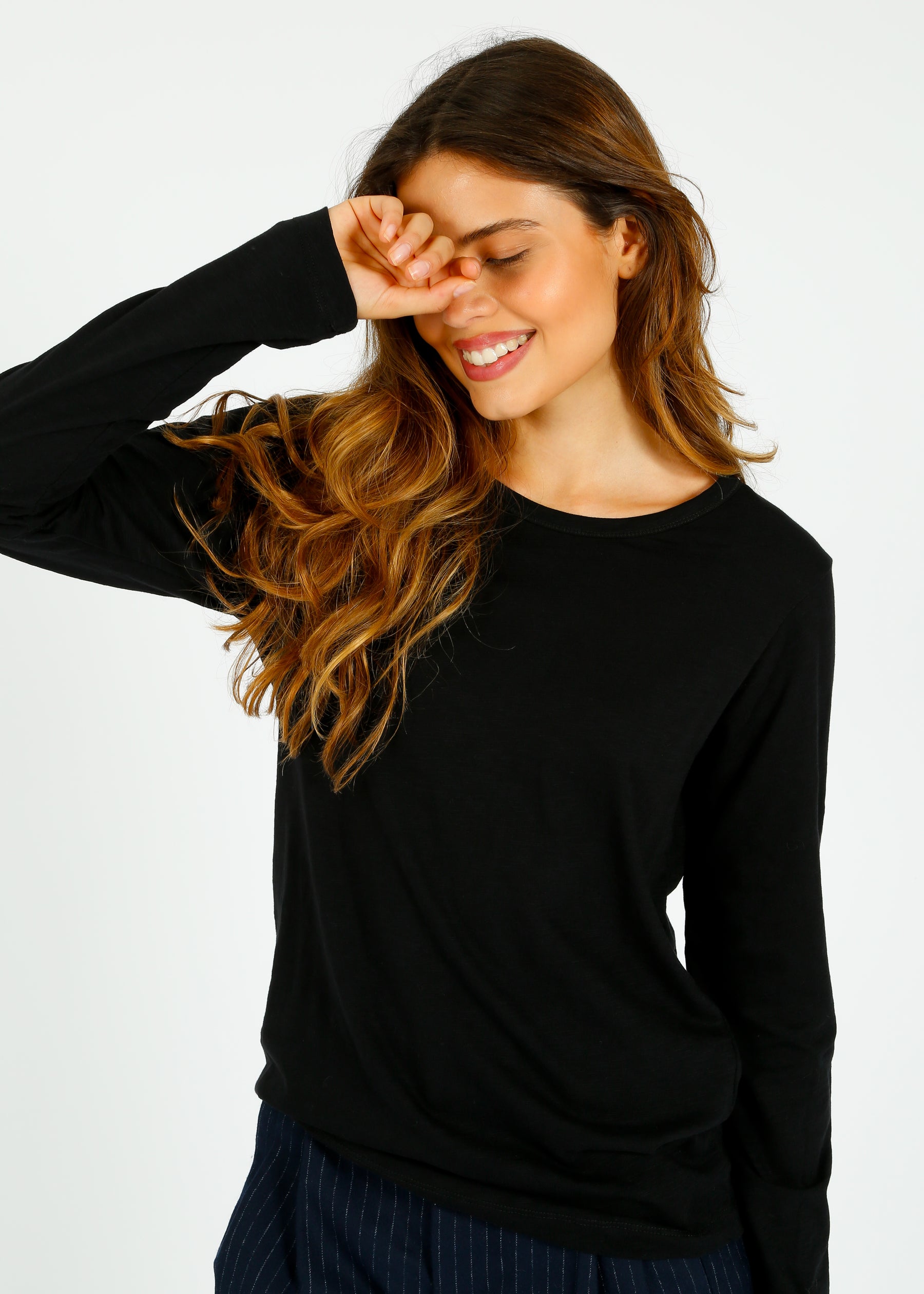 A woman smiling and wearing a black long-sleeved t-shirt with a round neckline.