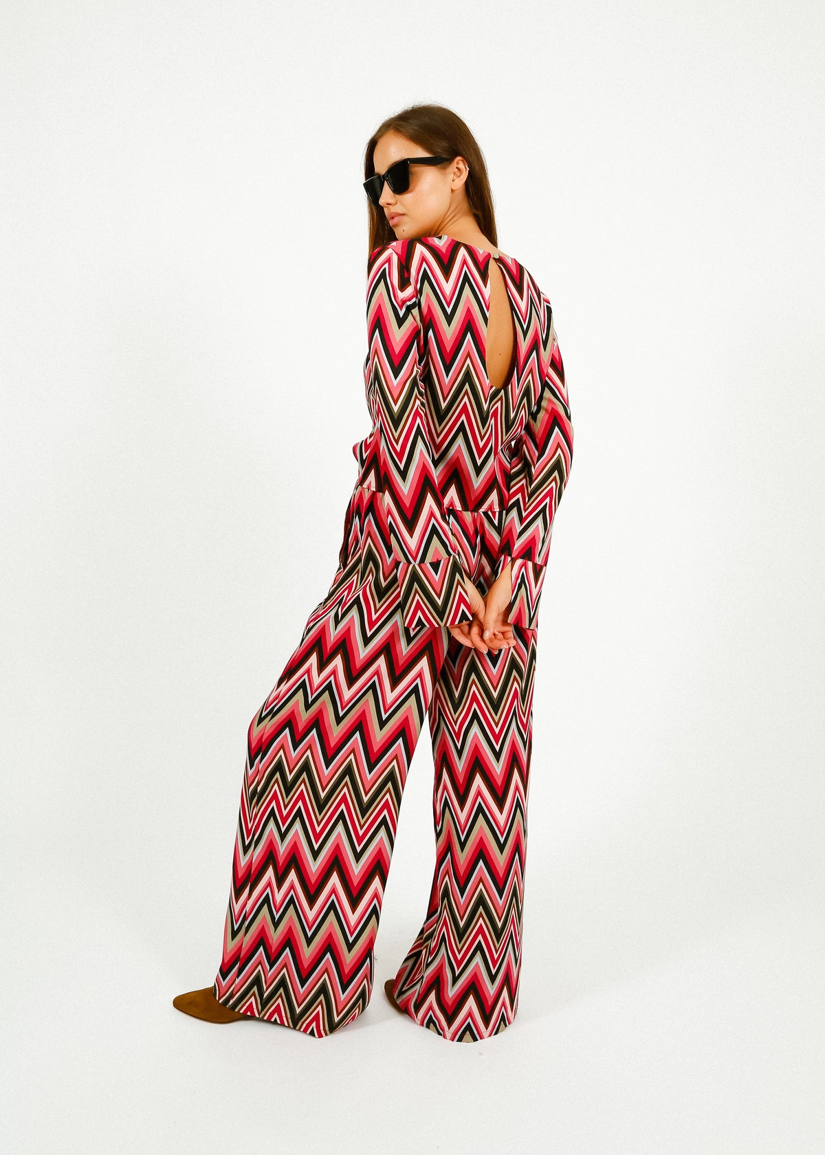 Woman wearing a red and black zigzag patterned jumpsuit on a white background