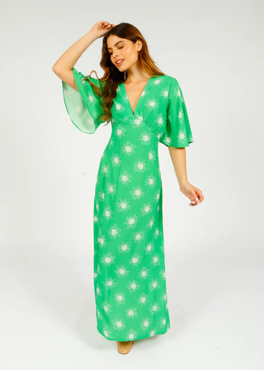 A woman wearing a green midi dress with a floral pattern, featuring a V-neck and flutter sleeves.