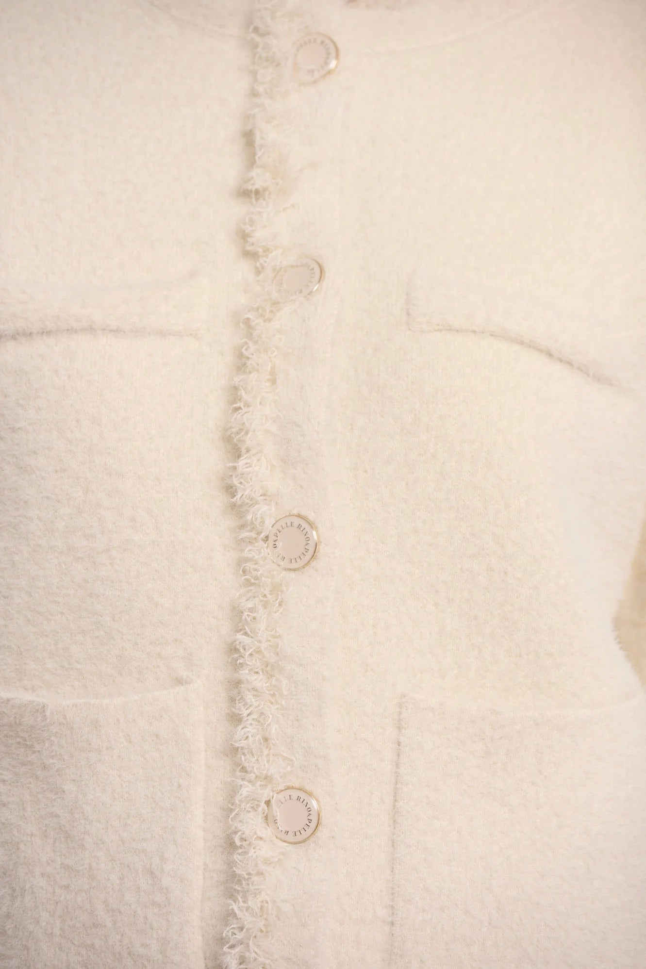 Rino & Pelle Vanna Jacket with Fringe in Birch Close-up of a textured white fabric with button details